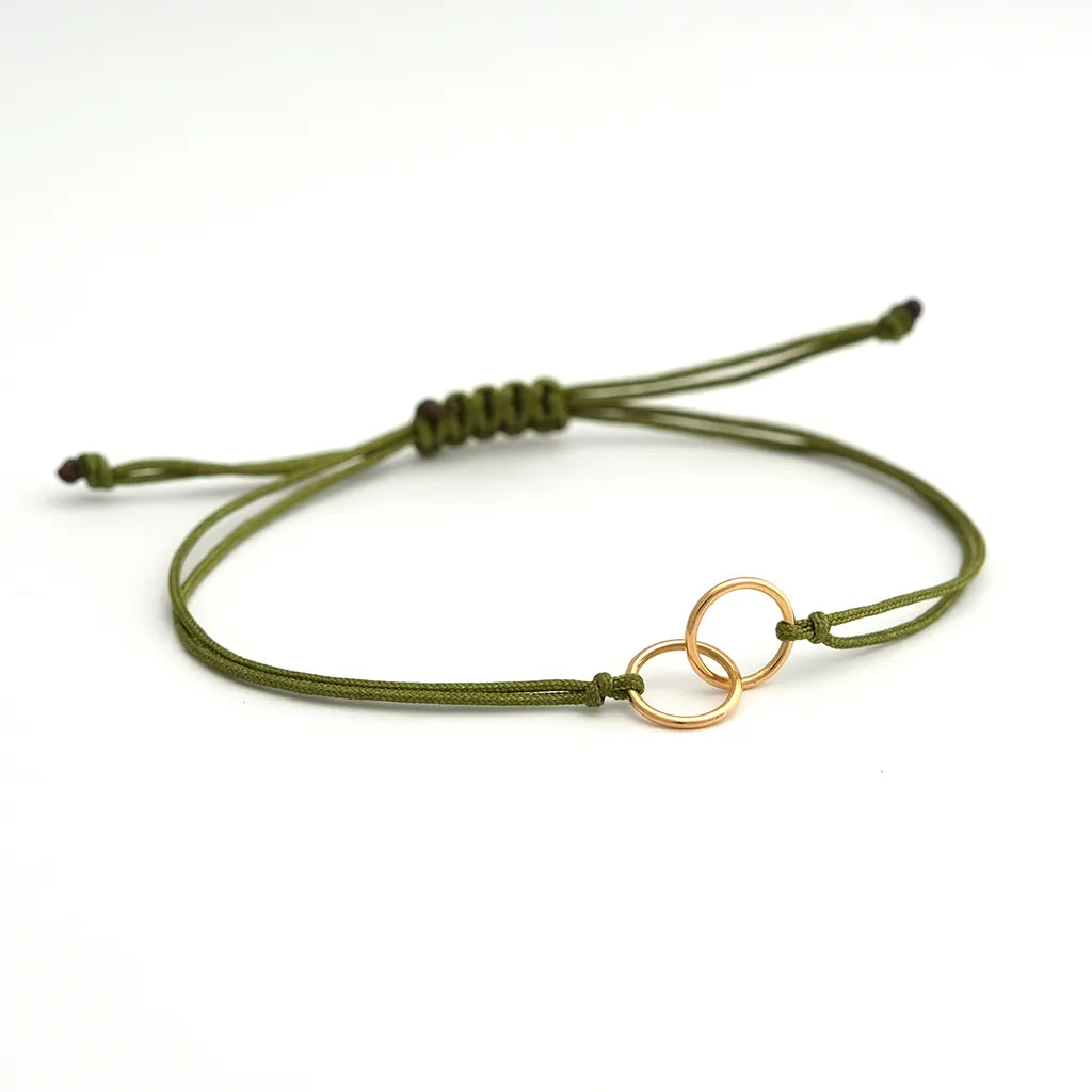 armband_aus_nylonband_olivgrün_geknotet_an_mittelteil_2_ringe_ineinander_gehaengt_gelbgold