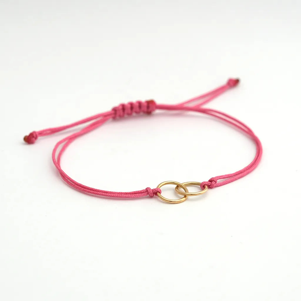 armband_aus_nylonband_pink_geknotet_an_mittelteil_2_ringe_ineinander_gehaengt_gelbgold