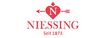 Logo_Niessing_herz_mit_pfeil_schmuckikonen_seit_1873_Zeitgemässes_Design_pure_Form_und_höchste_Qualität_Jedes_Niessing_Schmuckstück_ist_ein_wertvolles_Original-spannringe-niessing-schnur_anhaenger_kugeln_colette_goldfarben
